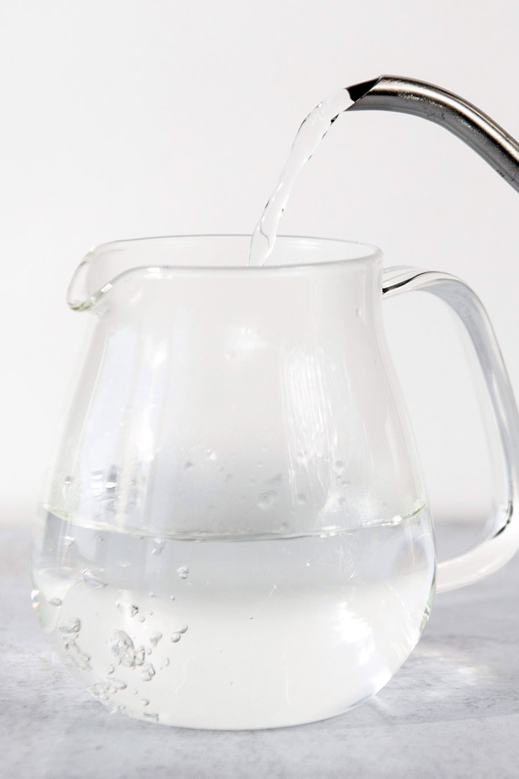 Pouring hot water into a glass teapot.