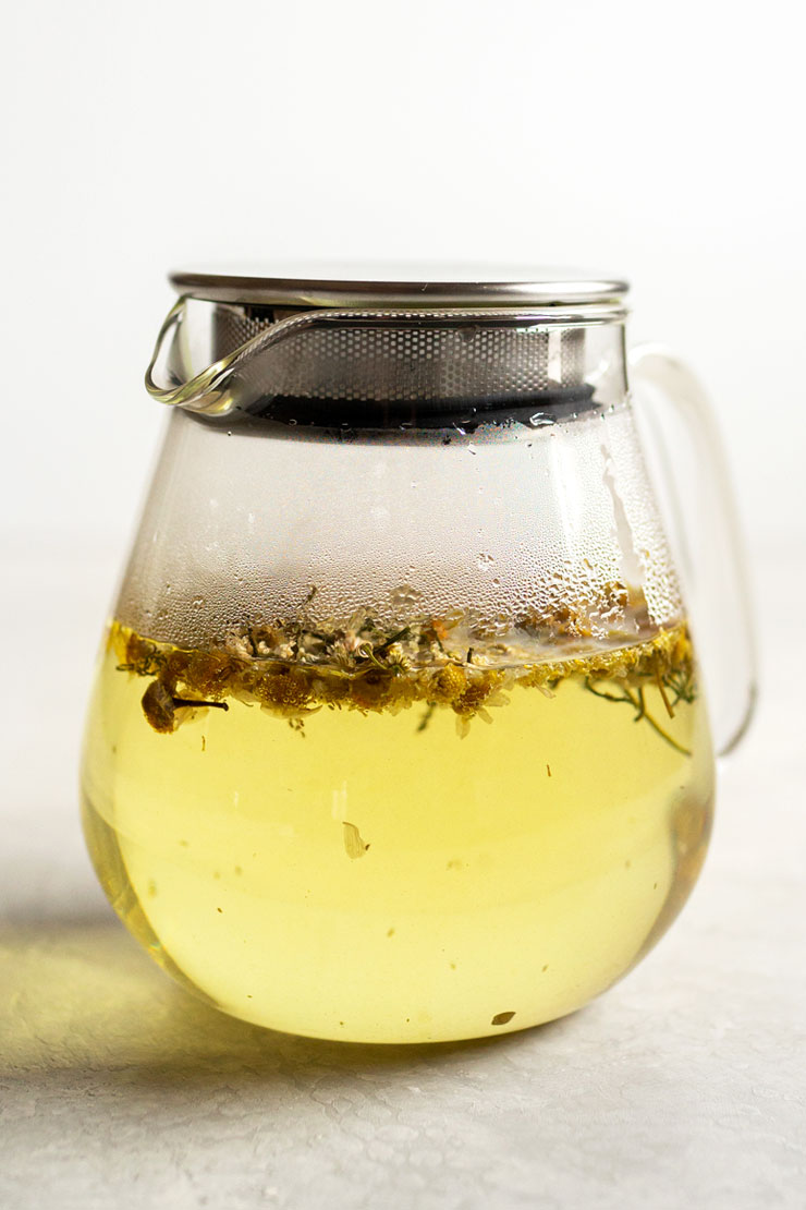 Chamomile tea in a glass teapot.