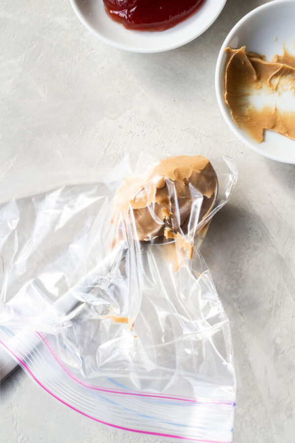 Spooning peanut butter into a sandwich bag. 