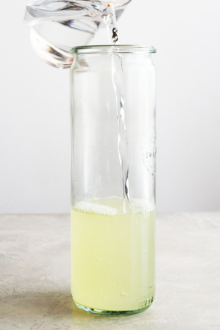 Pouring water into lemon juice in a tall jar