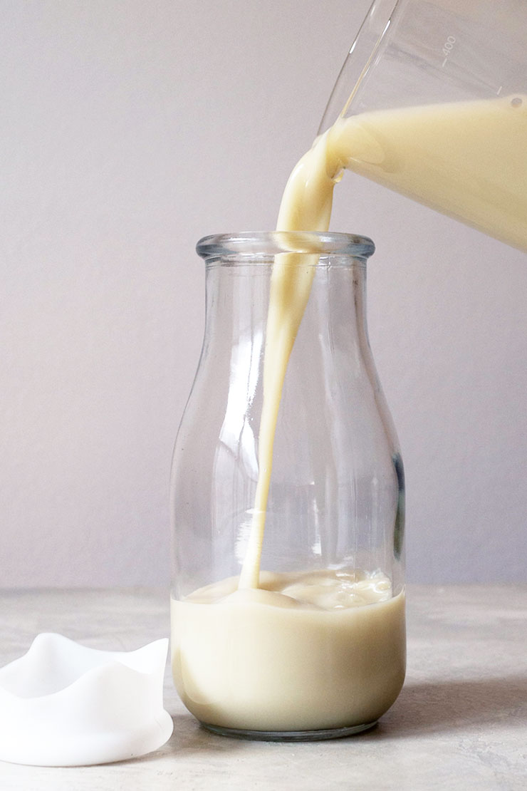 Pouring oat milk into a milk bottle.