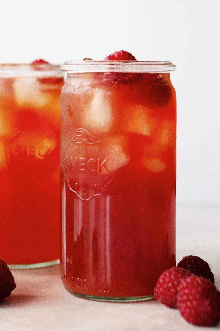 Raspberry iced tea in jars and fresh raspberries.