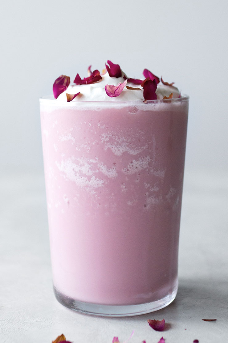 Frozen pink drink in cup with dried rose petals