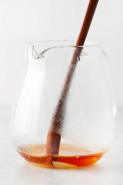 Wooden spoon stirring sugar into black tea in teapot.