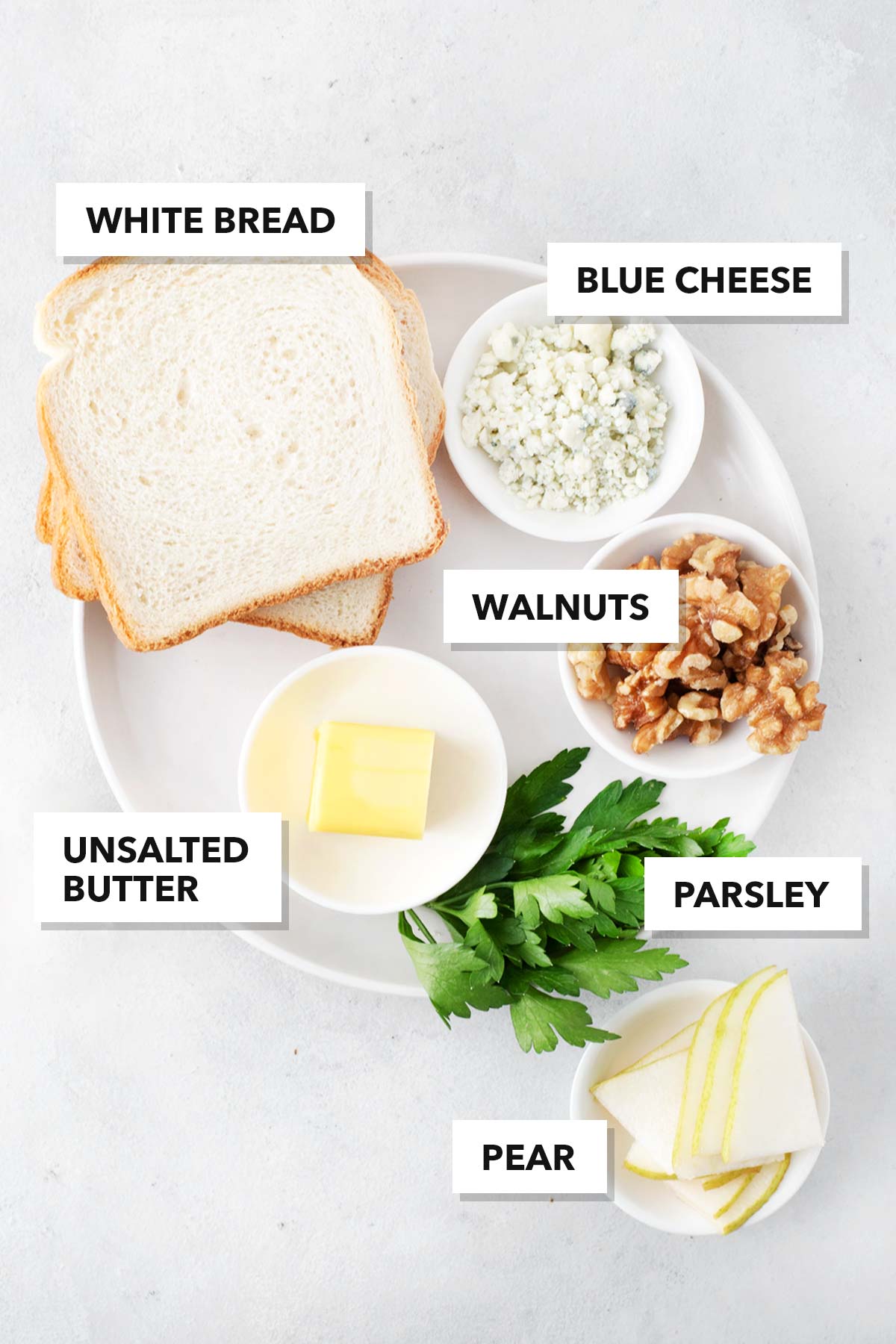 Ingredients for Blue Cheese and Pear Tea Sandwiches measured in bowls on a plate.