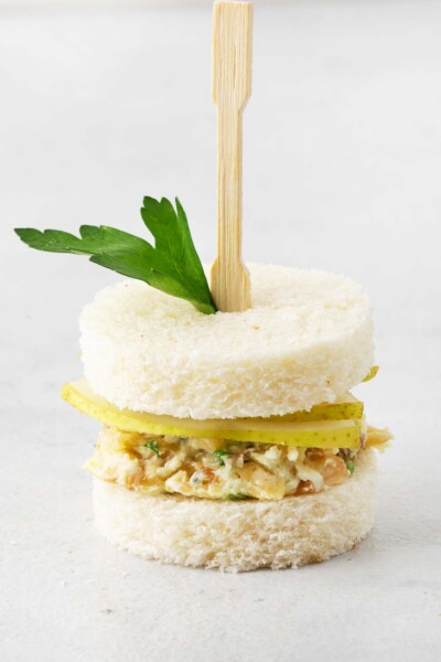 Blue Cheese and Pear Tea Sandwiches topped with parley and a cocktail fork.