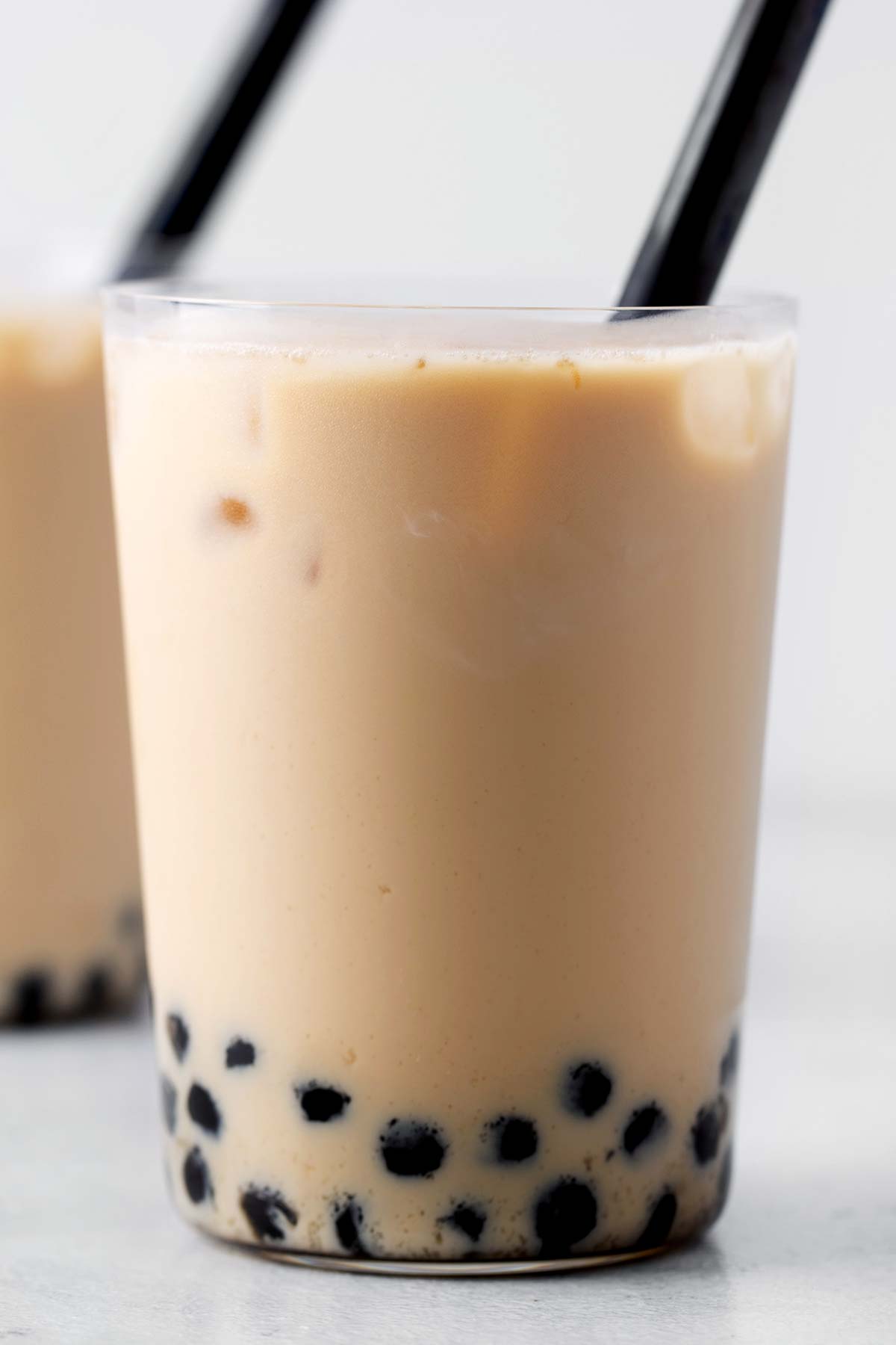 Bubble Tea, or Boba Milk Tea, in a clear glass with a wide, black straw.
