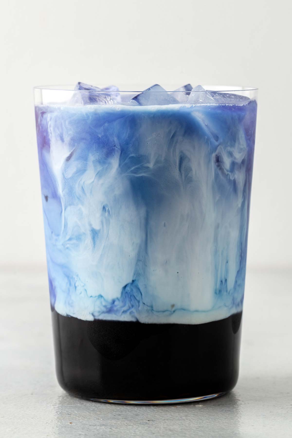 Butterfly Pea Flower Bubble Tea (Butterfly Pea Flower Milk Tea with Boba) with the blue tea and white milk swirling together in a glass.