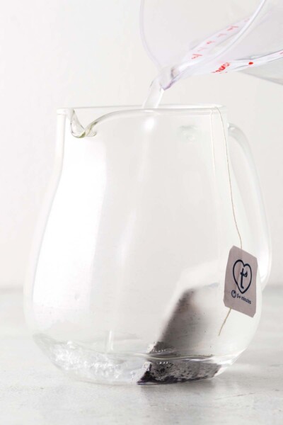 Pouring water onto tea bag in a teapot. 