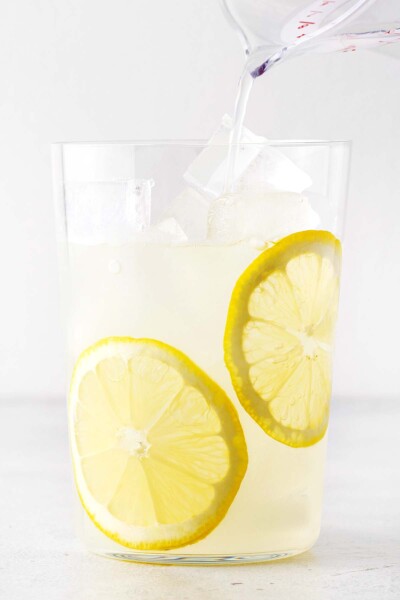 Pouring lemonade into a cup with ice. 
