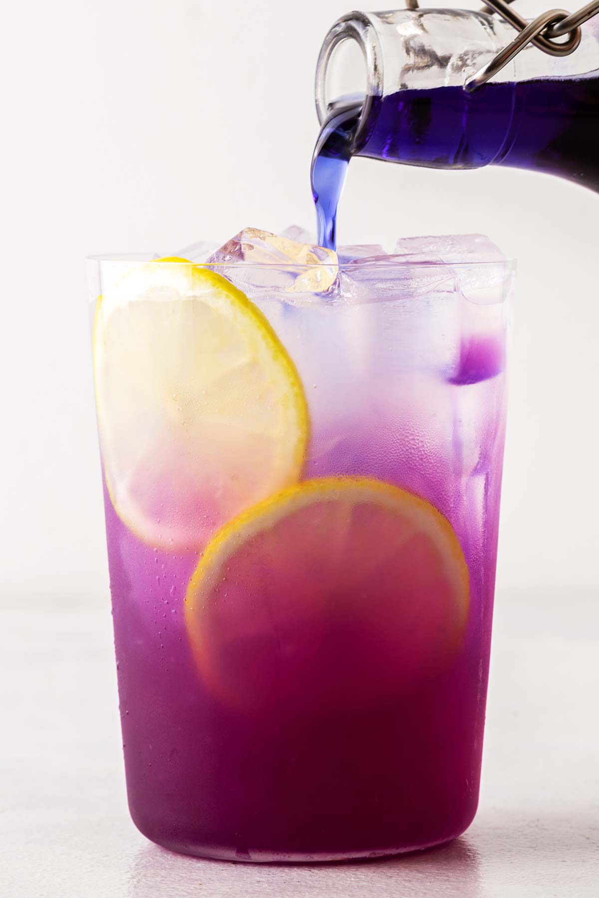 Butterfly Pea Flower Syrup being poured into a clear glass of lemonade.