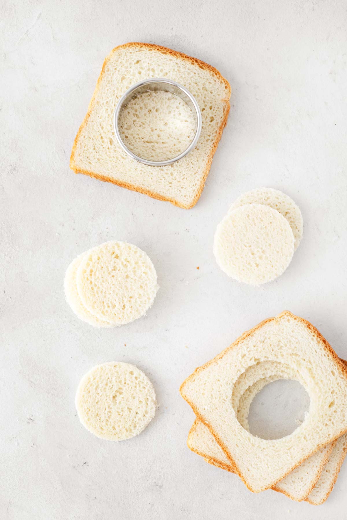 White bread being cut into circles with a round cookie cutter.