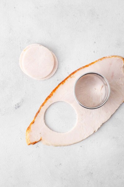 Sliced turkey being cut into circles with a round cookie cutter.