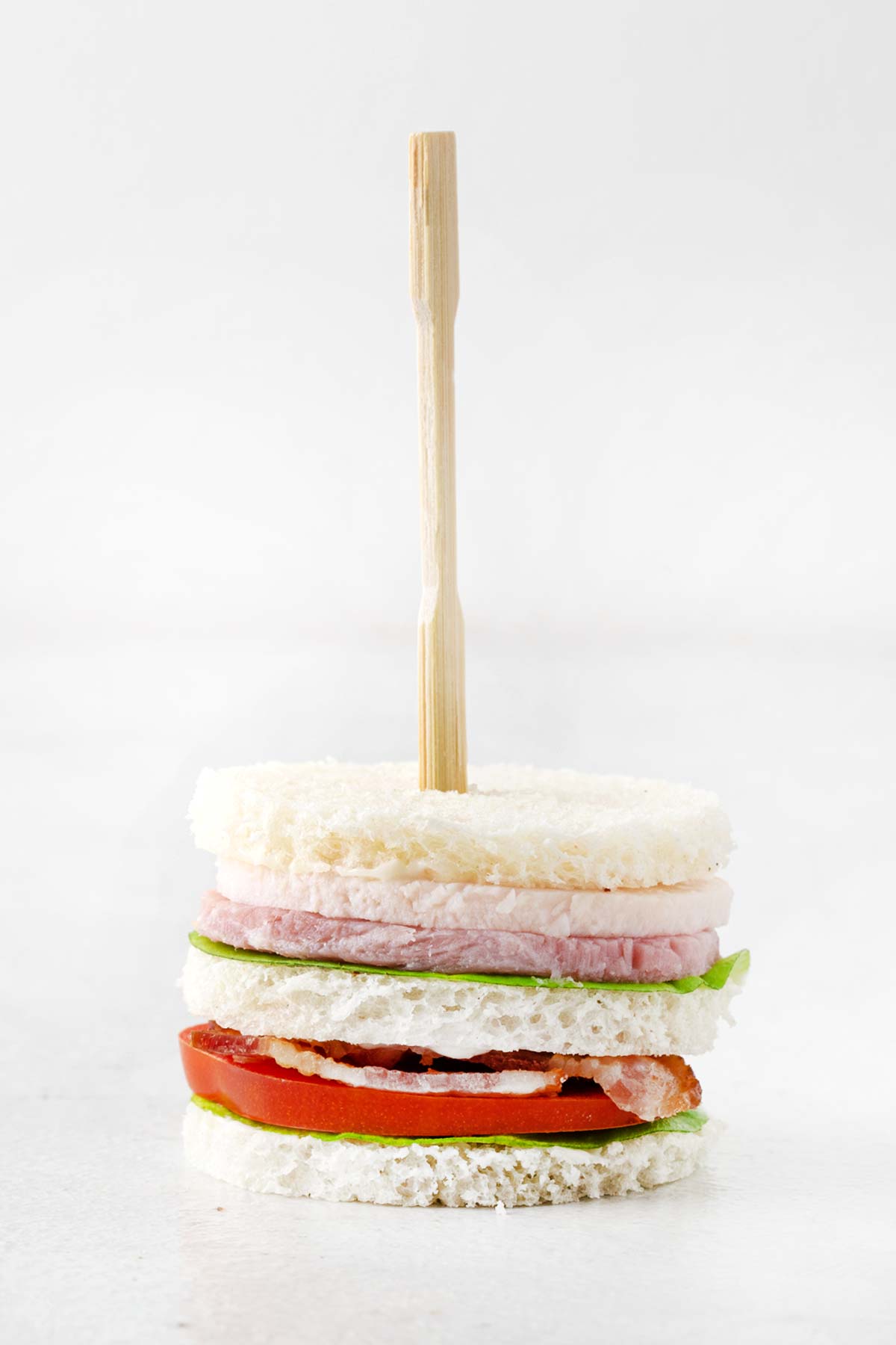Completed club tea sandwich skewered with a cocktail fork. 
