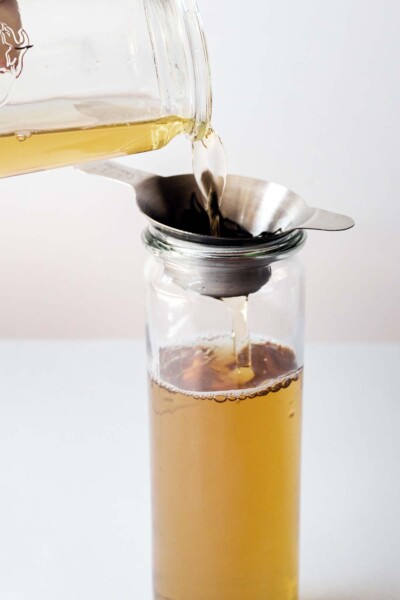 Straining tea leaves into a glass container. 