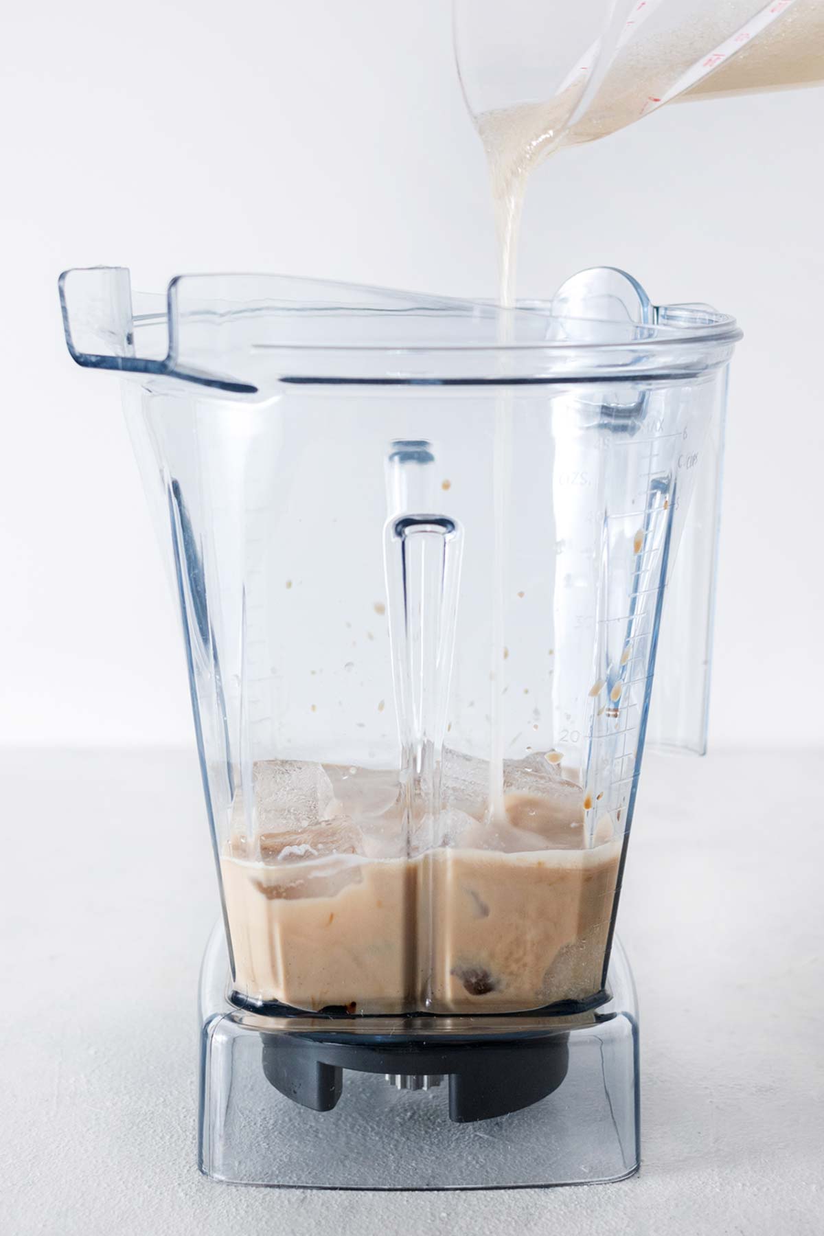 Espresso, instant coffee, milk, ice, and homemade Frappuccino base syrup in a blender cup.