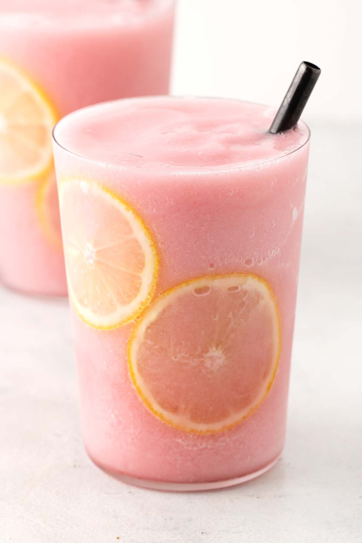 Frozen Hibiscus Lemonade in clear cup with straw.