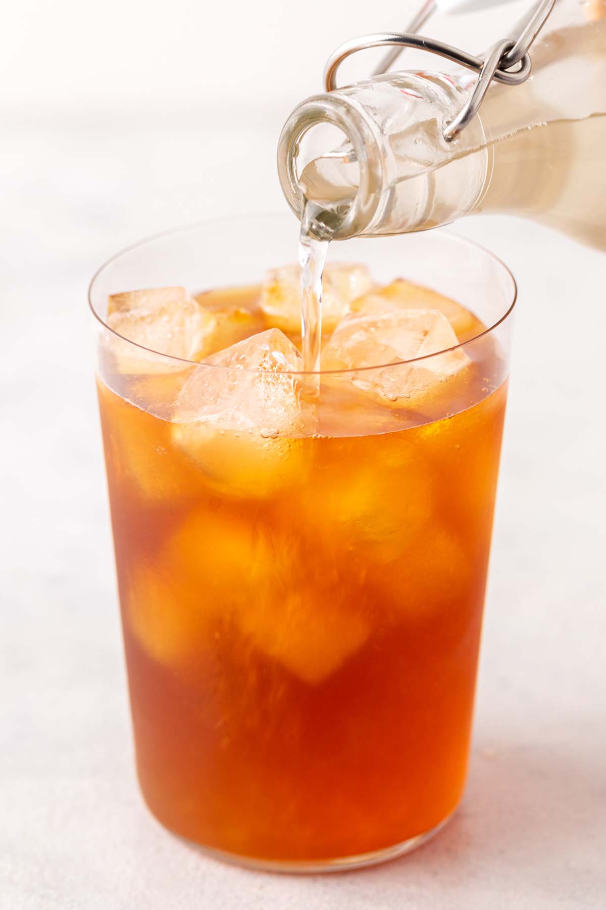 Simple Homemade Ginger Syrup poured into iced tea in clear glass.