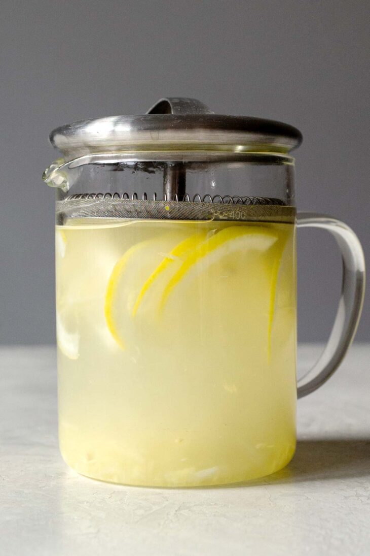 Teapot with lemon slices, grated ginger, and hot water.