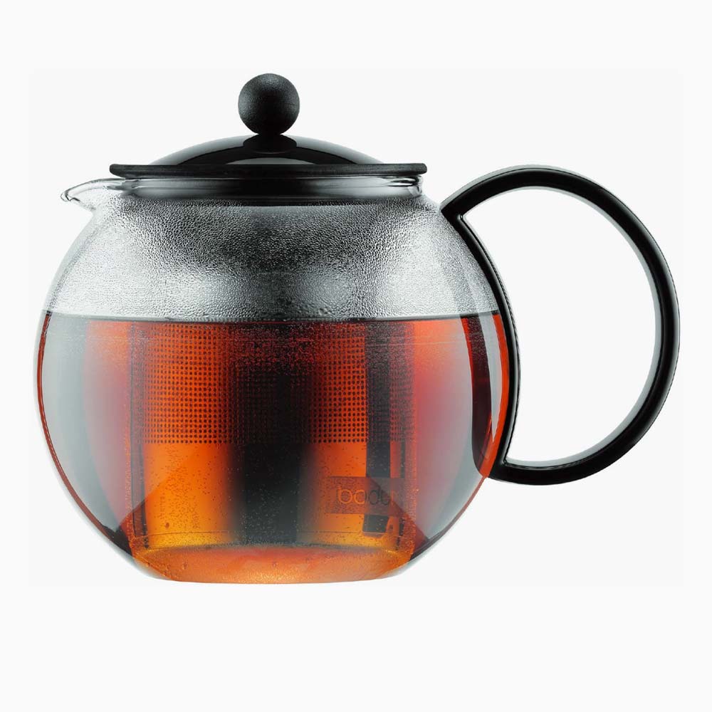 Glass teapot with black lid and handle with brewed tea inside.