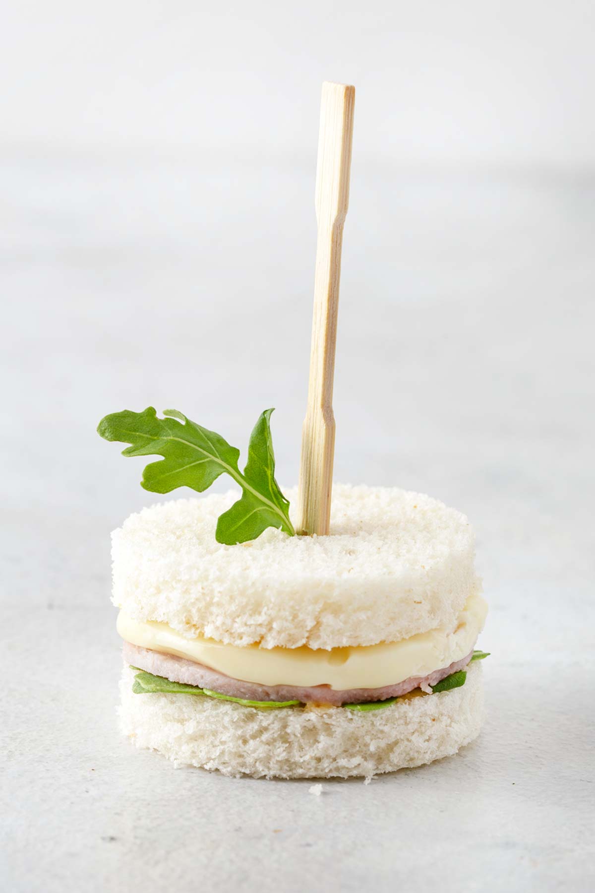 Ham and brie cheese tea sandwich with a cocktail fork.
