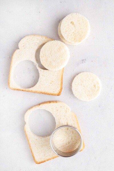 Cutting circles out of the bread using a round cookie cutter.
