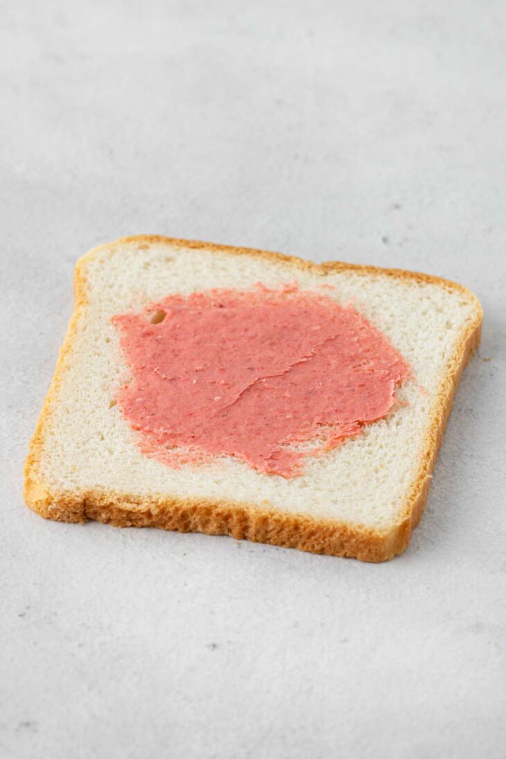 Strawberry cream cheese spread on a slice of bread.