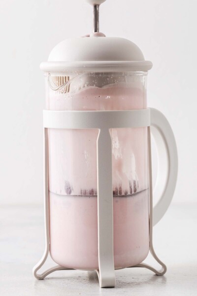 Plunging hibiscus cold foam in a French press.