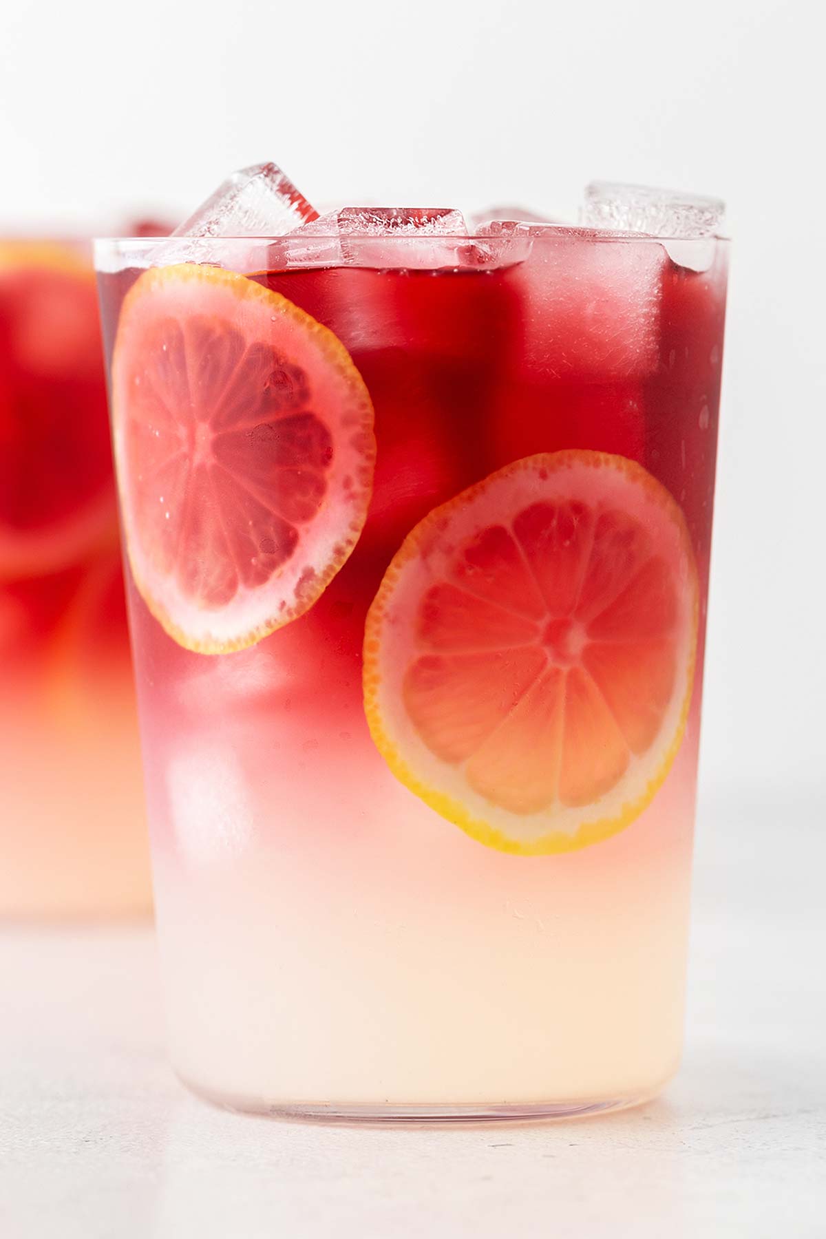 Hibiscus Lemonade in a clear glass with lemon slices.