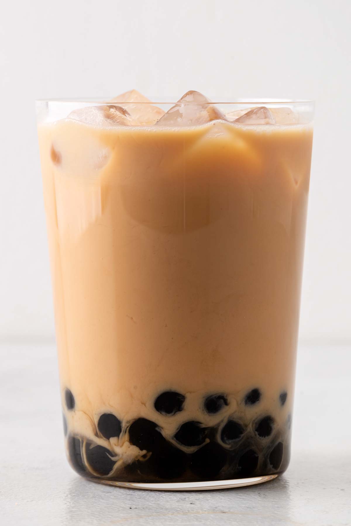 Finished Hong Kong Milk Tea (Hong Kong Bubble Tea) in a clear glass with boba at the bottom and ice on top.
