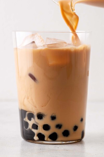 Pouring tea into a cup with ice and tapioca balls. 