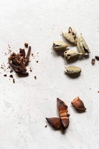 Crushing star anise, cloves, and cardamom pods.