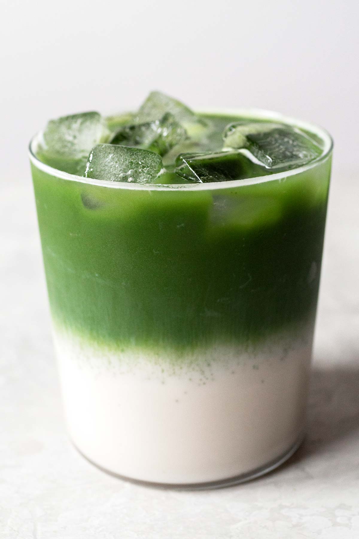 Iced matcha latte, layered, in a glass cup.