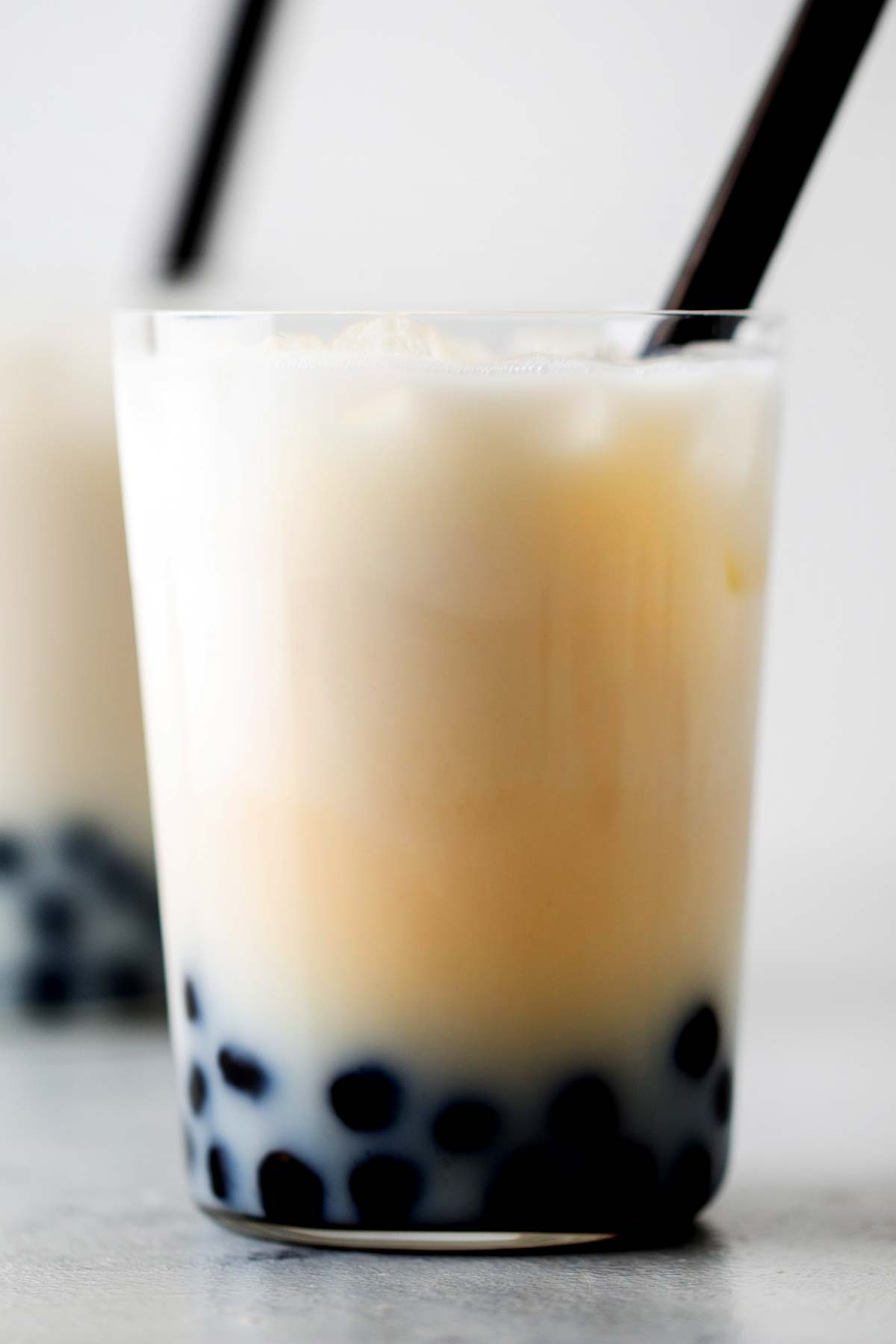 Jasmine Boba Milk Tea in a glass with a black straw.