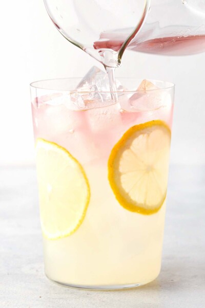 Pouring lavender tea into a cup with lemonade and ice. 