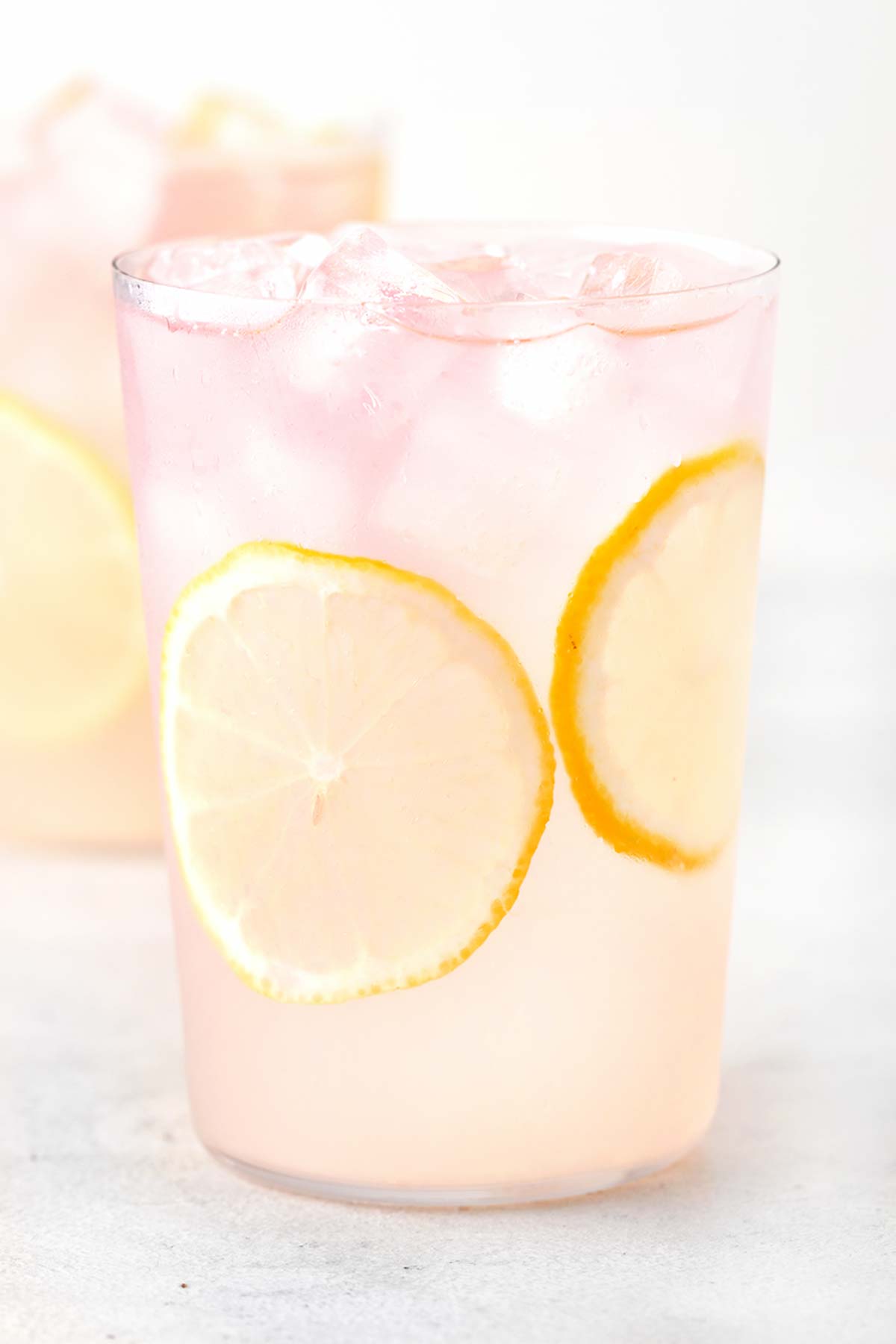 Lavender Lemonade in clear glass with sliced lemons.