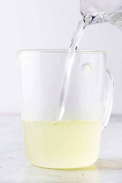 Pouring hot water into a cup with lemon juice.