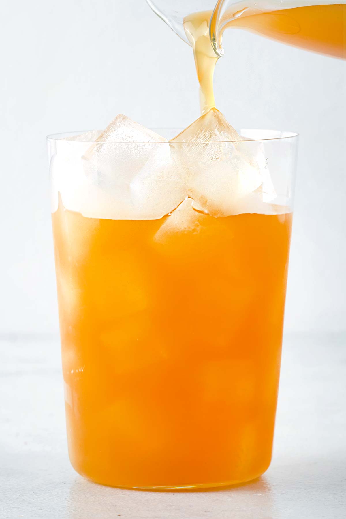 Mango Iced Tea being poured into clear cup filled with ice.