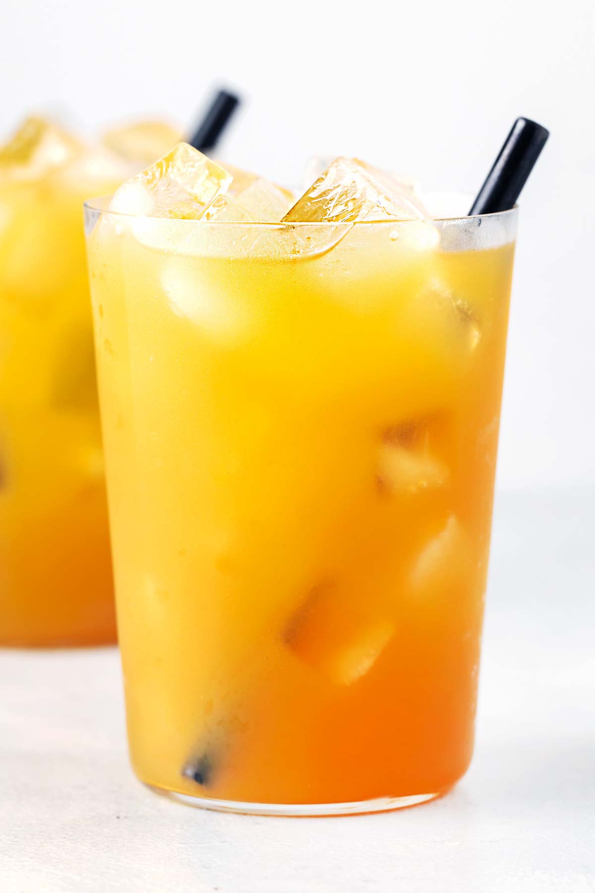 Mango Iced Tea in clear cup with straw.