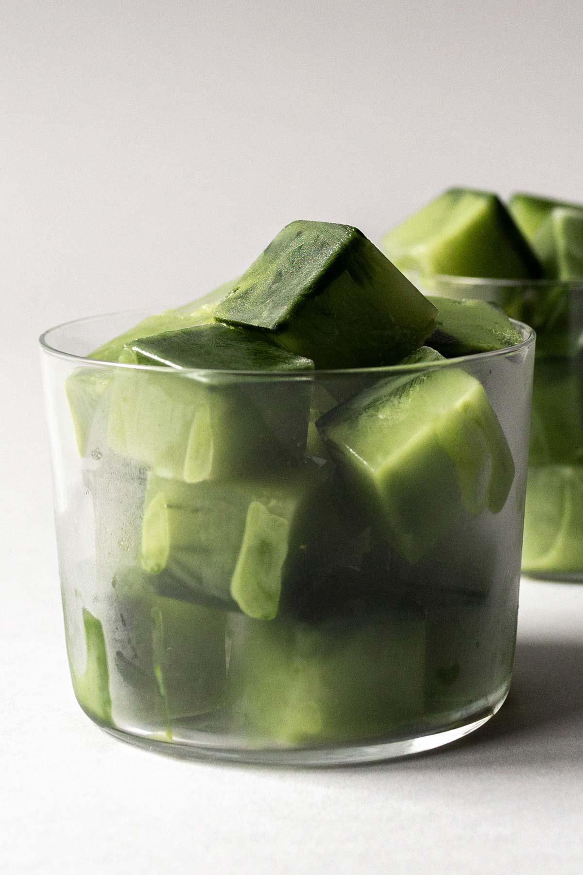 Matcha green tea ice cubes in glass cups.