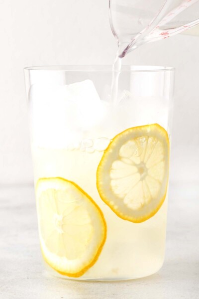 Pouring lemonade into a cup with ice and lemonade