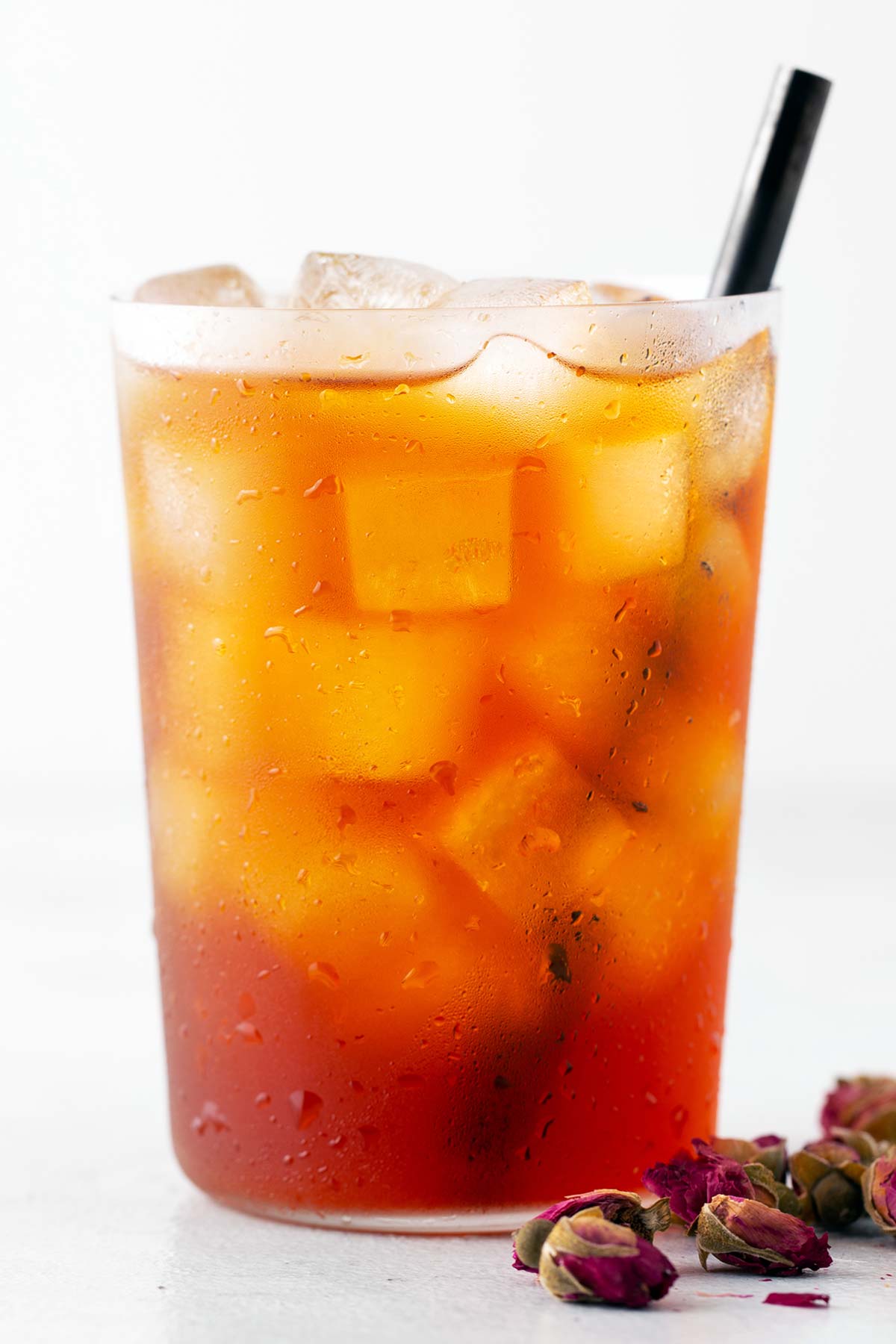 Rose iced tea in a cup with a black straw.