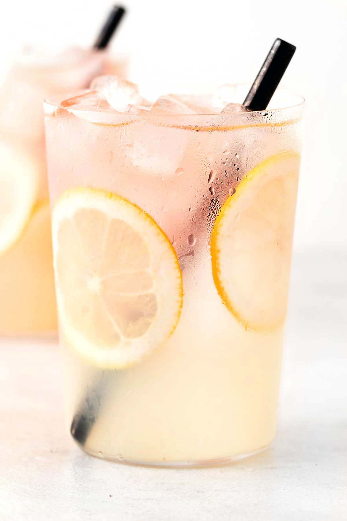 Rose Lemonade in clear cup with sliced lemons.
