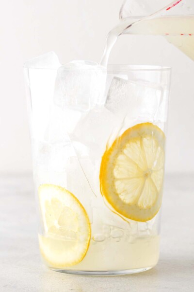 Pouring lemonade into a cup with ice and lemons. 