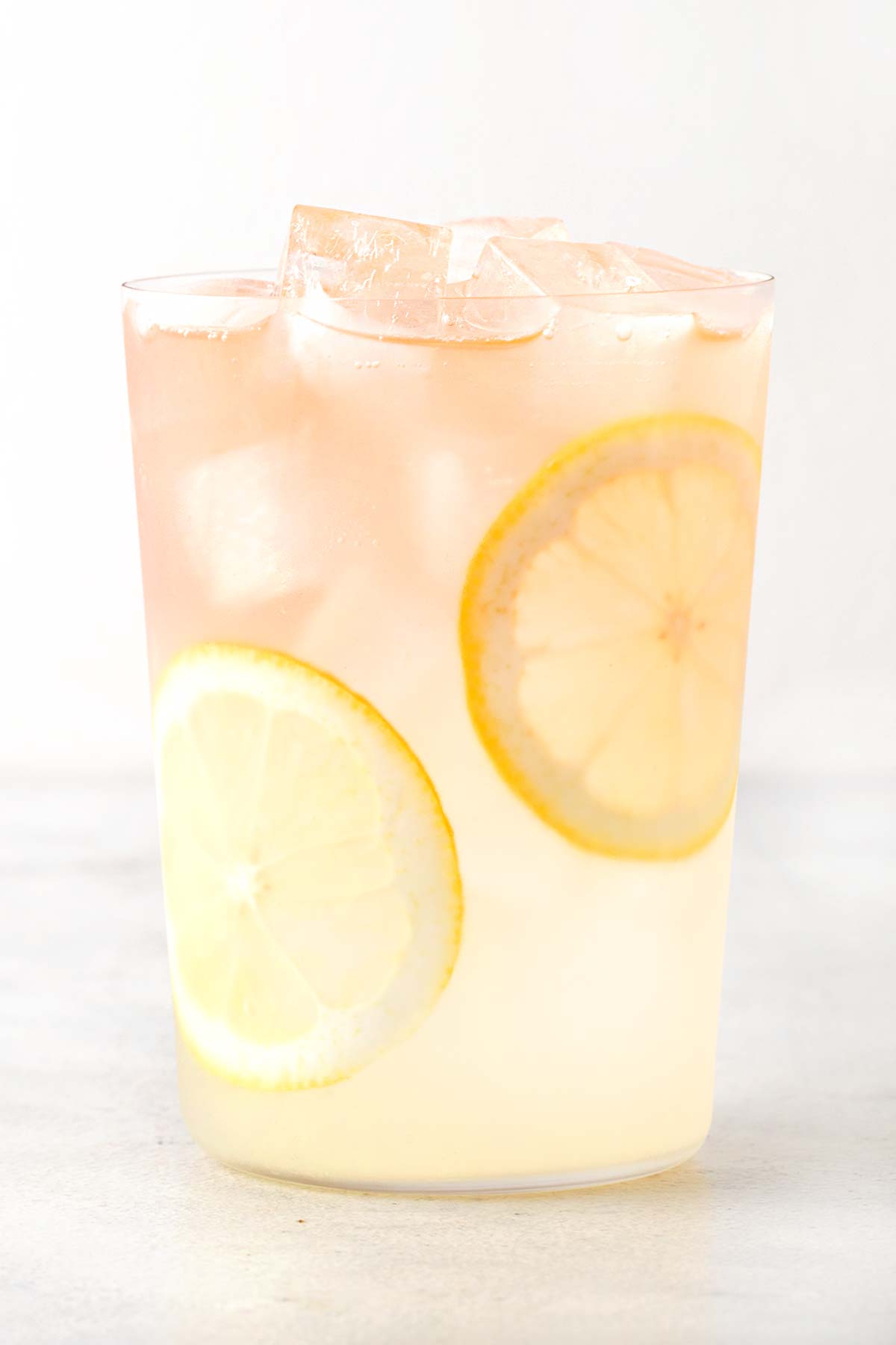 Rose Lemonade in clear cup with sliced lemons.