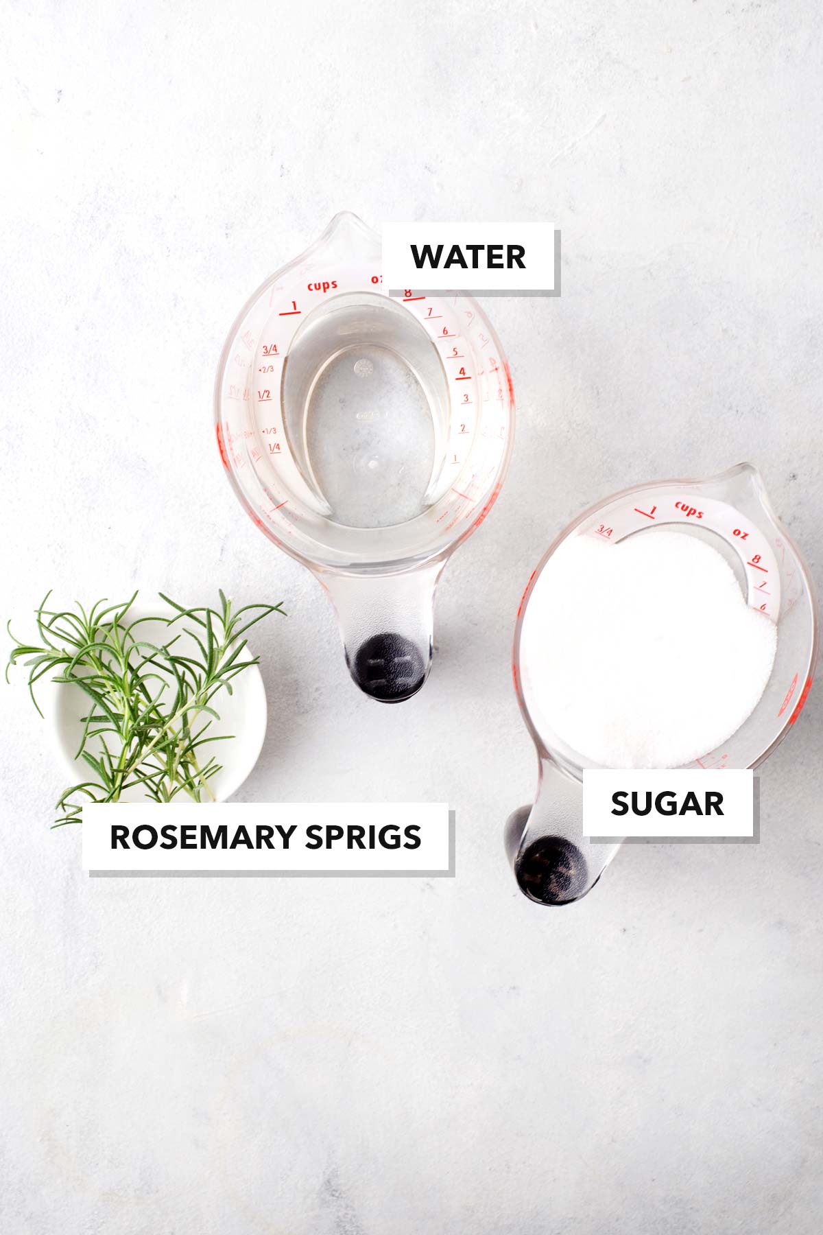 Simple Homemade Rosemary Syrup ingredients in measuring cups and labeled.