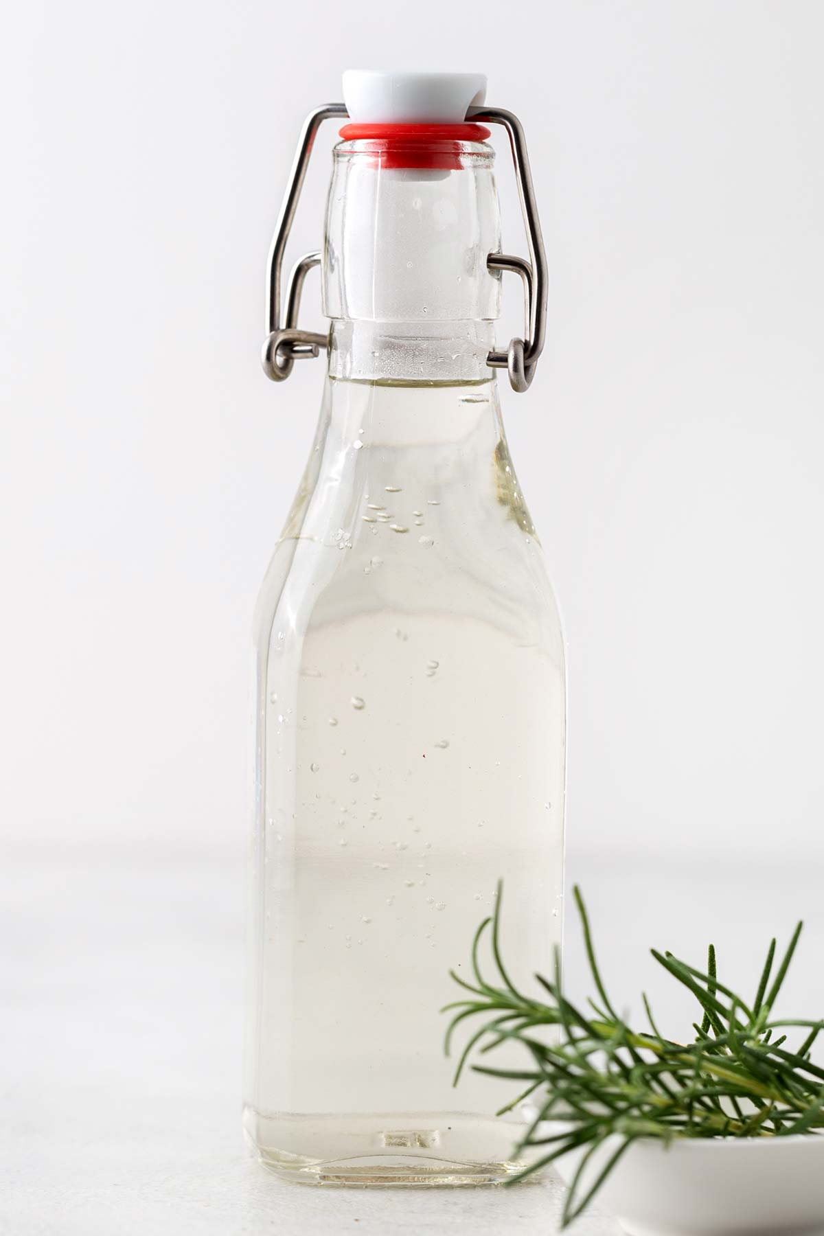 Rosemary syrup in a glass container.