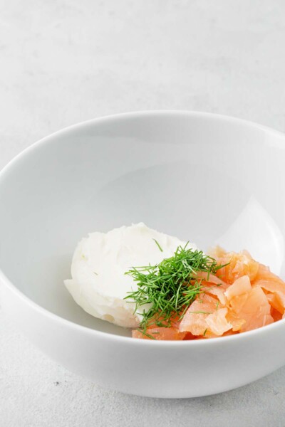 Smoked salmon, cream cheese, and dill in a white bowl.