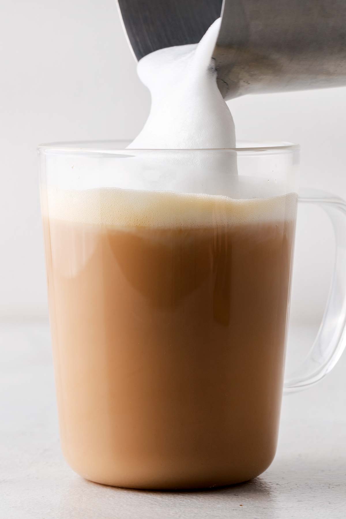 Starbucks Royal English Breakfast Tea Latte Copycat finished drink in a clear glass with the milk foam being poured on top.