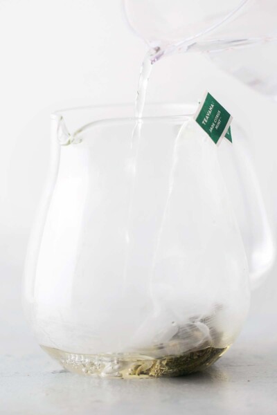 Pouring water on tea bags in a teapot. 